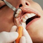 A dentist examining a patient's teeth Description automatically generated with medium confidence